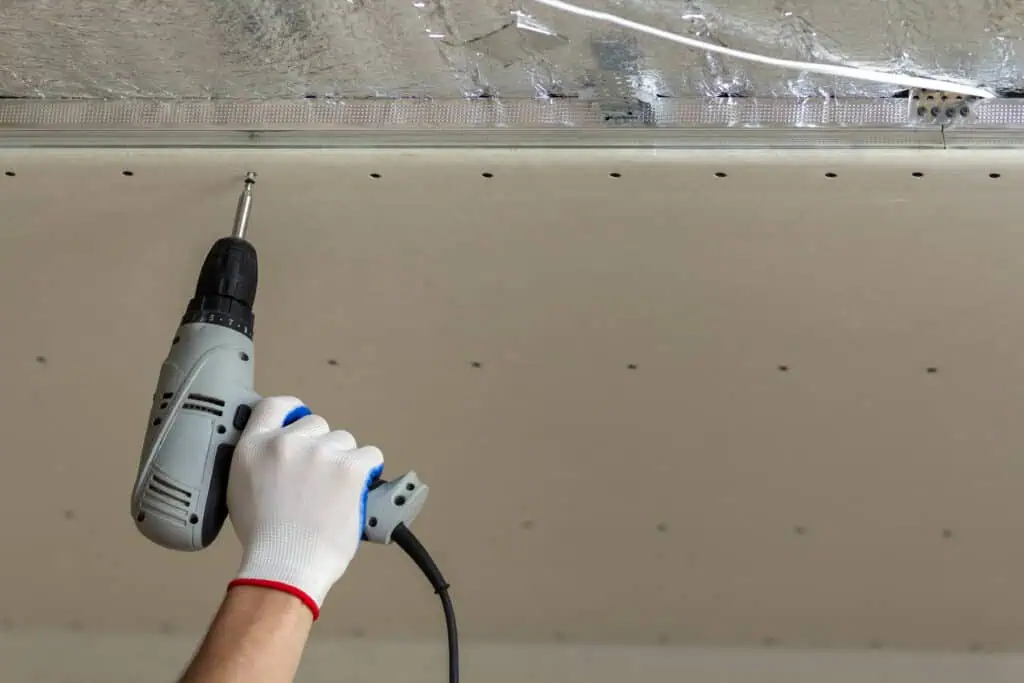 Drill being used for ceiling installation or renovation in a home or commercial space.