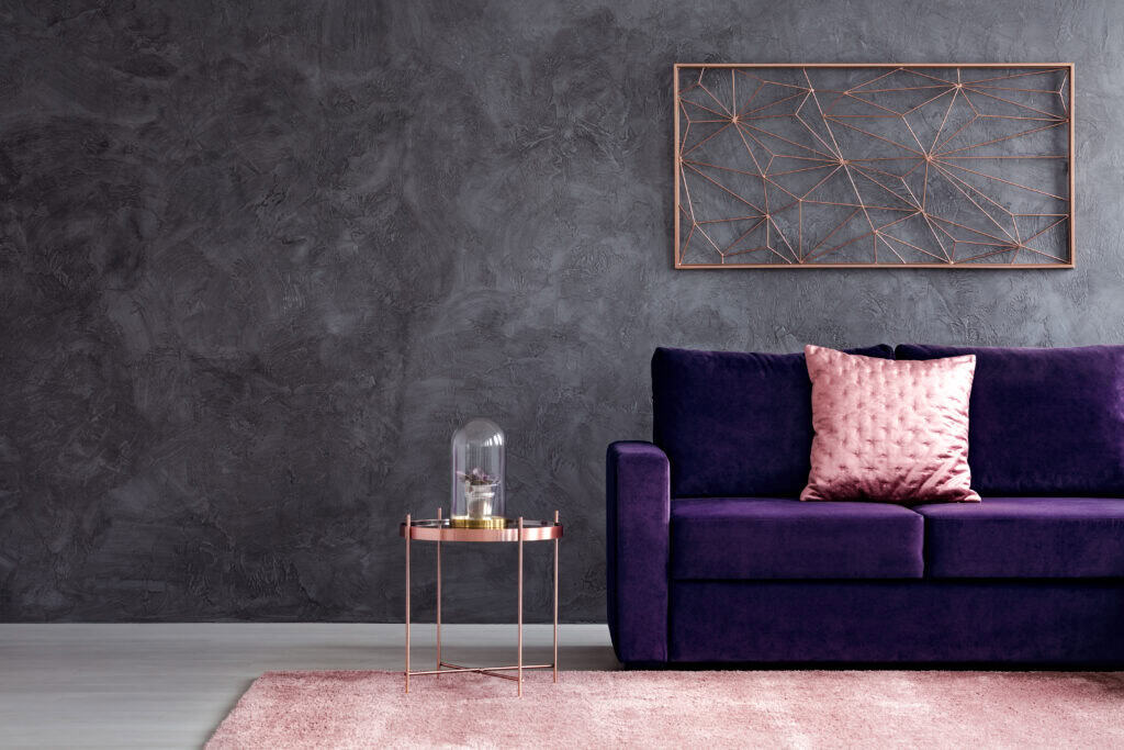 Modern living room with purple velvet sofa, pink throw pillow, and contemporary wall art.
