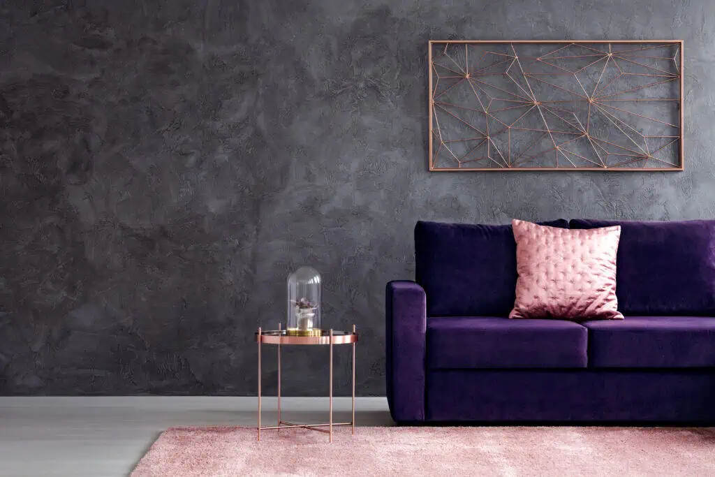 Modern living room with purple velvet sofa, pink throw pillow, and contemporary wall art.