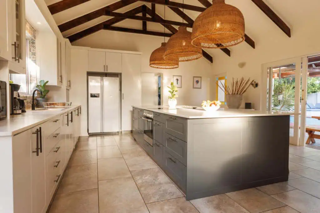 Modern kitchen with white cabinets, large island, and wooden pendant lights, featuring a spacious an.