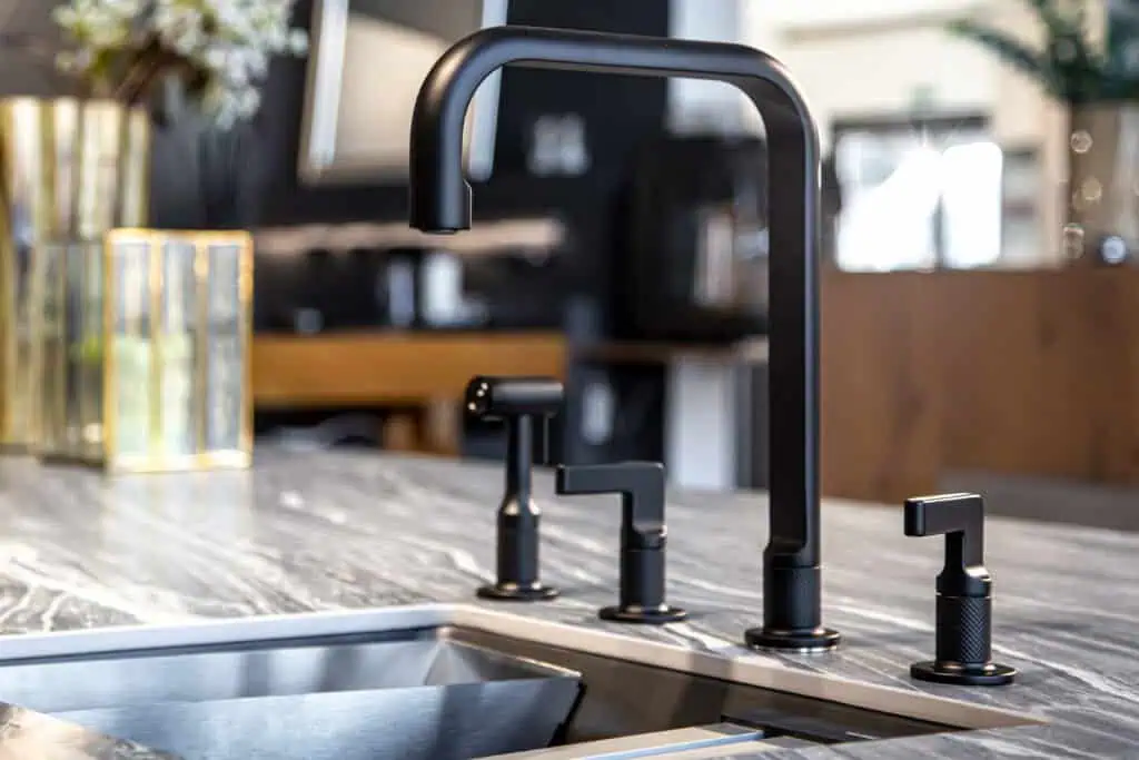 Modern black kitchen faucet with a pull-down sprayer over a stainless steel sink in a contemporary k.