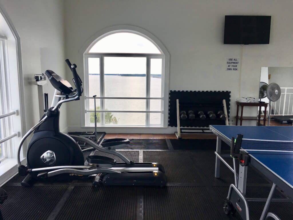 Home gym featuring elliptical trainer and ping pong table for versatile workouts and recreation.