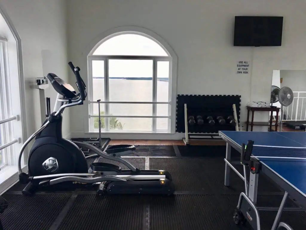 Home gym featuring elliptical trainer and ping pong table for versatile workouts and recreation.