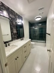 Contemporary bathroom with dual sinks, black fixtures, and a glass shower enclosure.