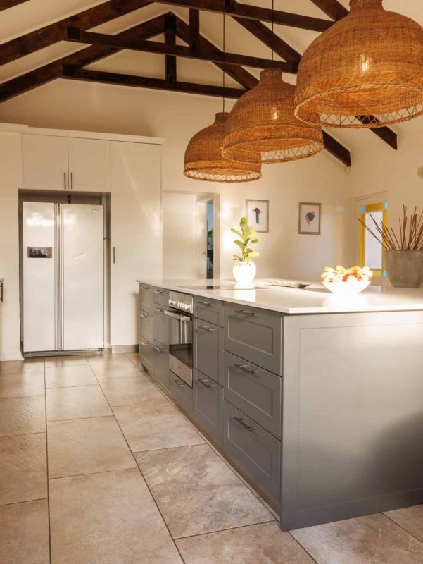 Modern kitchen with white cabinets, large island, and wooden pendant lights, featuring a spacious an.